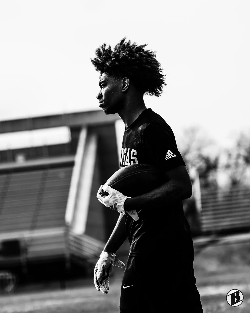 Athlete holding a football, seen in profile in black and white