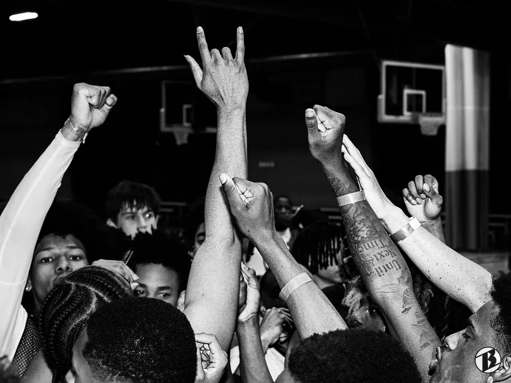 Athletes raise fists and hand signs in celebration at a showcase
