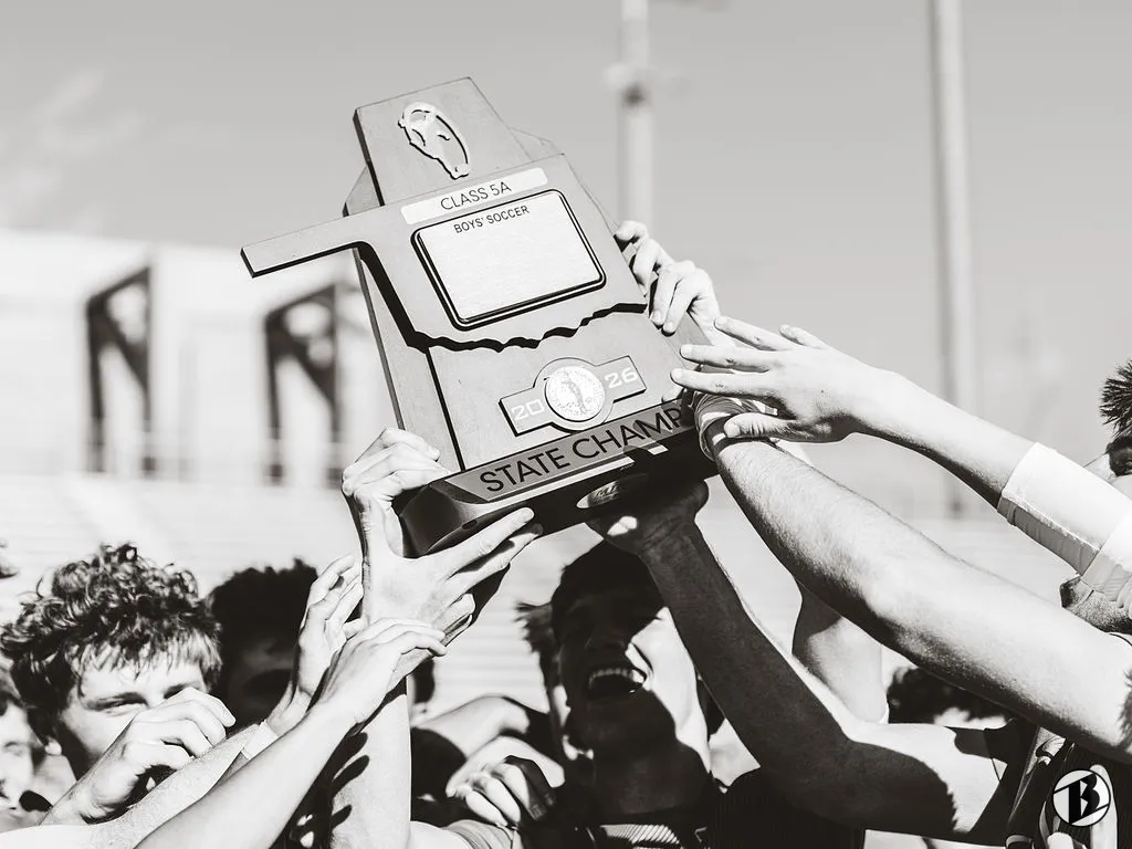 Players reach up to hold the Class 5A state championship trophy overhead