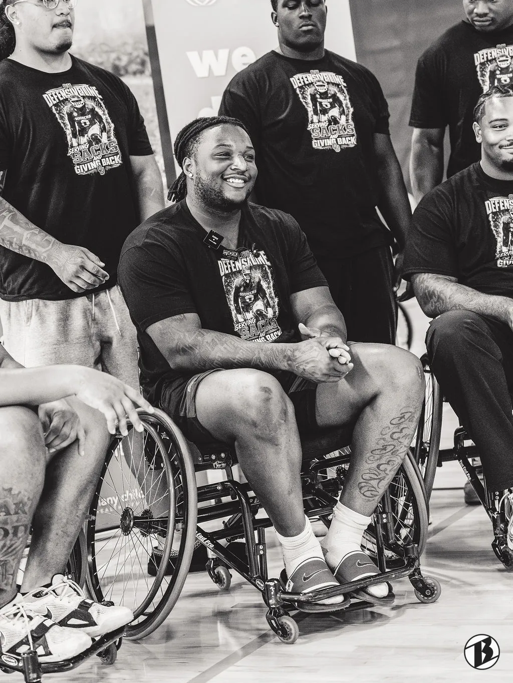 Smiling athlete in a wheelchair among a group at a youth parasports event