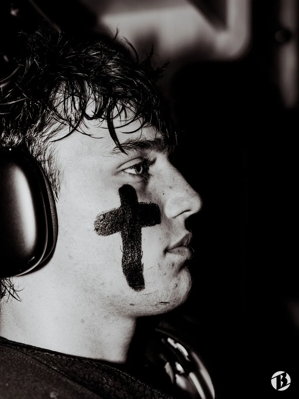 Football player in profile with a cross drawn in eye black on his cheek